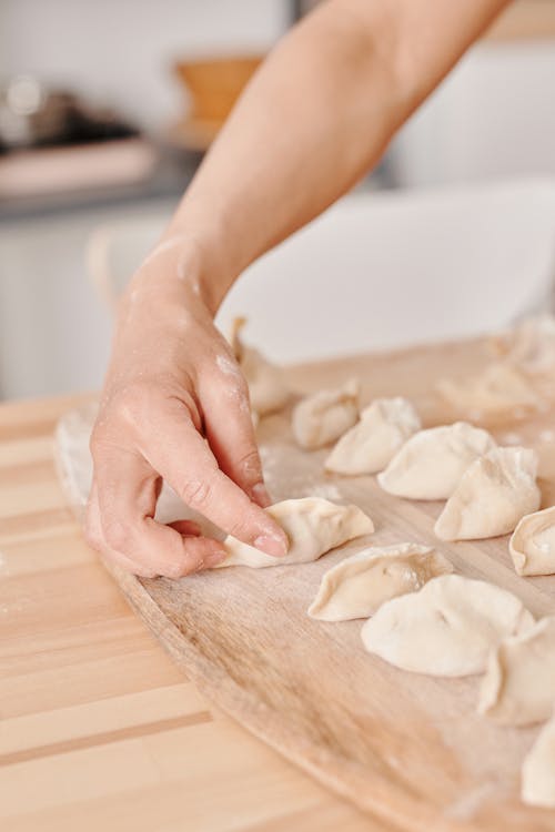 Person Holding Dough on Brown Wooden Tray