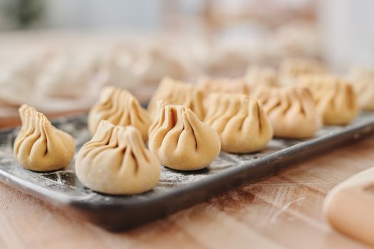 Close-up view of uncooked traditional dumplings on a floured tray, ready for cooking.