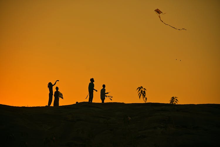 Silhouette Of People On Top Of Mountain During Sunset