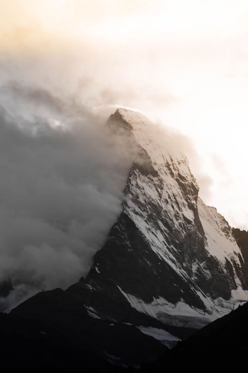 Free Dramatic view of snow-covered Matterhorn peak piercing clouds at sunrise in Zermatt, Switzerland. Stock Photo