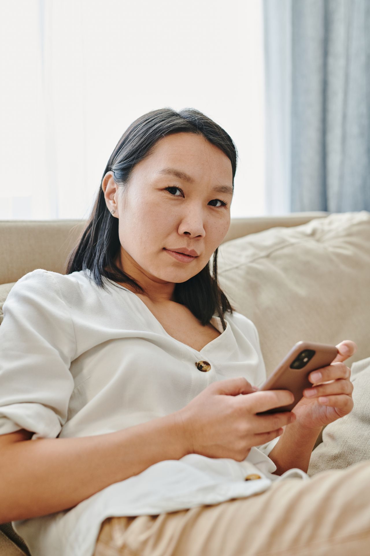 Người phụ nữ dùng điện thoại trên sofa
