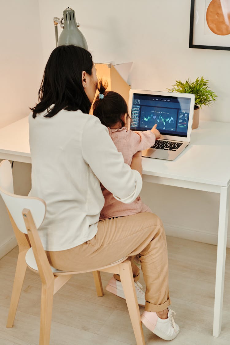 A Woman Using A Laptop With Her Child