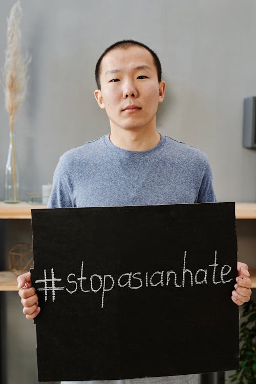 A Man in a Blue Shirt Holding a Black Signage