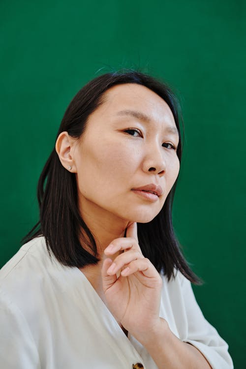 Gratis arkivbilde med asiatisk kvinne, grønn bakgrunn, hvit skjorte