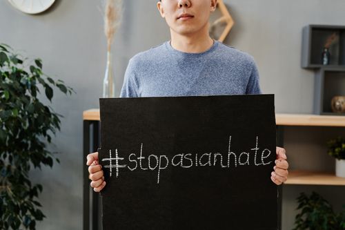 Free A person holding a sign promoting the message to stop Asian hate indoors. Stock Photo