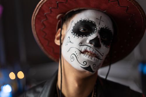 Free Portrait of a person wearing Day of the Dead makeup and traditional hat, capturing cultural artistry. Stock Photo