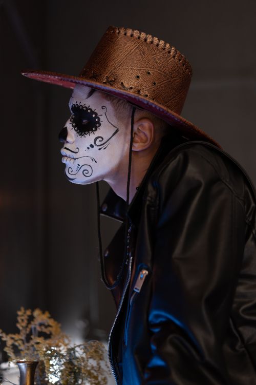 Free Side view of a person in Halloween makeup and costume wearing a leather jacket and hat. Stock Photo
