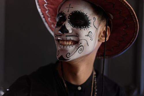 Free Man with Dia de los Muertos face paint and traditional hat smiling warmly. Stock Photo