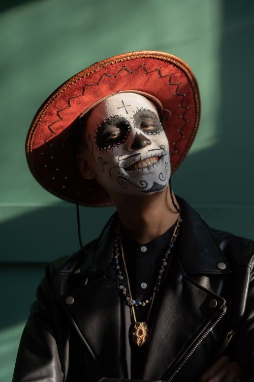 Free Portrait of a man wearing Day of the Dead makeup and a traditional sombrero, smiling warmly. Stock Photo