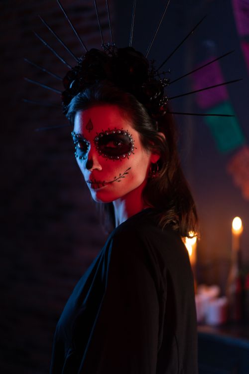 Free A woman in dramatic Day of the Dead sugar skull makeup with candles in the background. Stock Photo