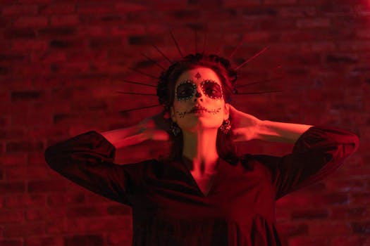 Artistic portrait of a woman with Day of the Dead makeup and halo under red lighting.