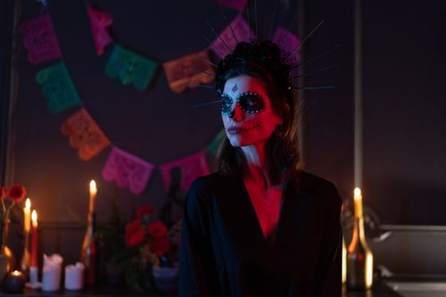 Free Woman dressed for Day of the Dead with face paint and headdress in a festive setting. Stock Photo