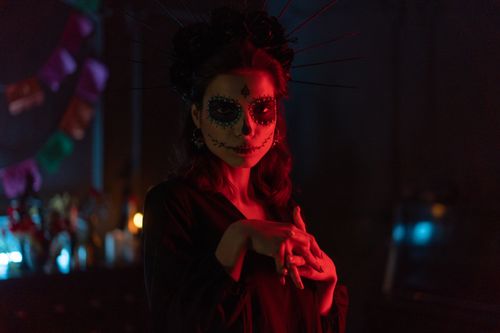Free A woman in Day of the Dead makeup in a dimly lit, creative setting, embracing tradition and artistry. Stock Photo