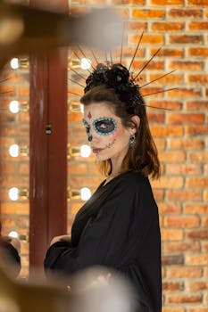 Woman with Día de los Muertos makeup and costume against brick wall background.