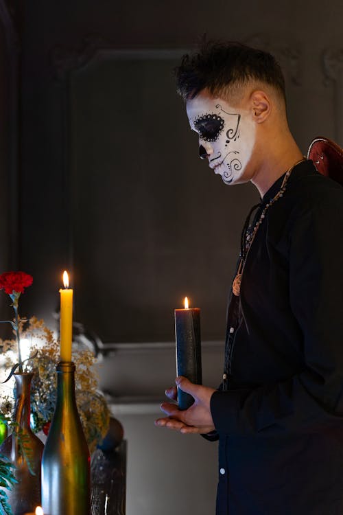 A Man with Face Paint Holding a Lighted Candle
