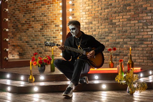 A Man in a Sugar Skull Makeup Playing Guitar