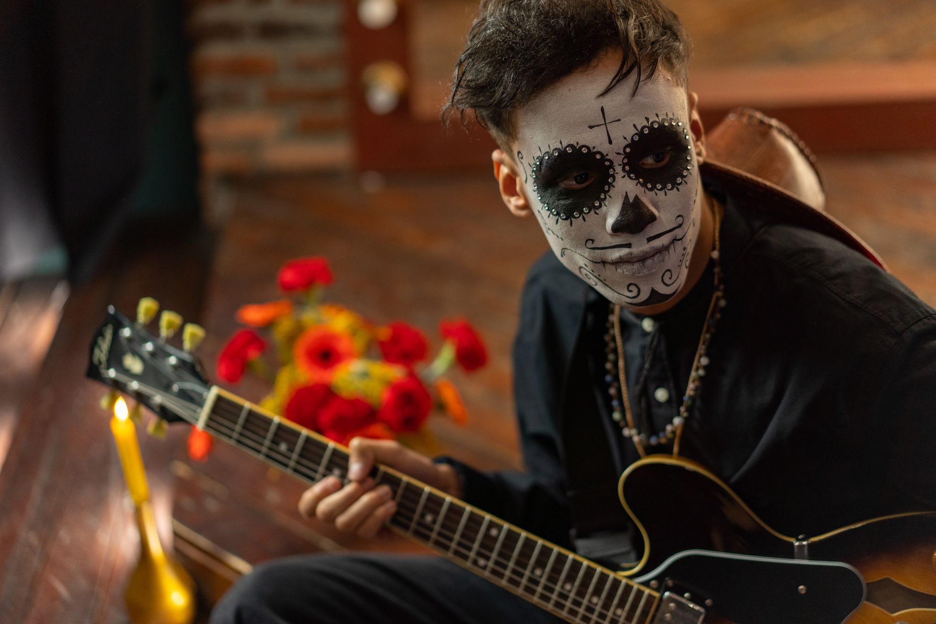 Musician with face paint playing guitar on Day of the Dead celebration.