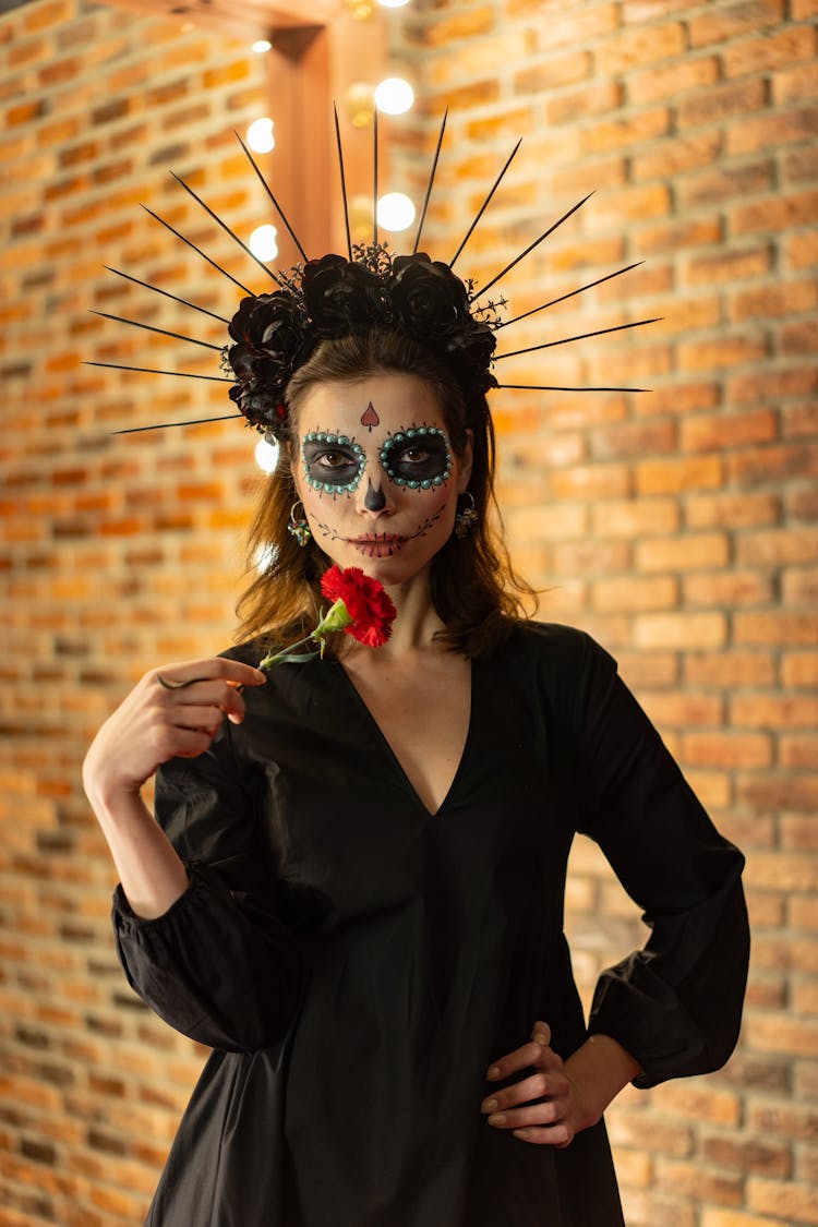 A Woman With Skeleton Face In Black Long Sleeves Holding A Flower