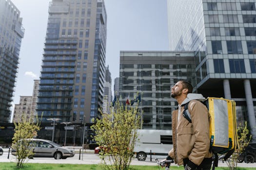 Delivery person with thermal bag in a modern cityscape setting, conveying urban logistics.