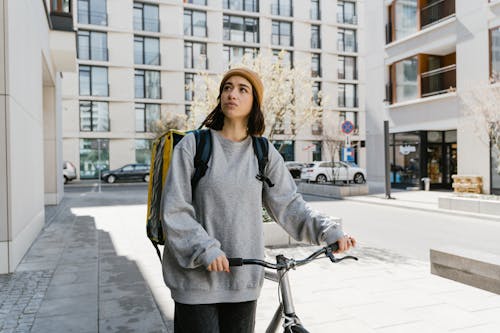 Woman in Gray Sweater Standing on the Sidewalk