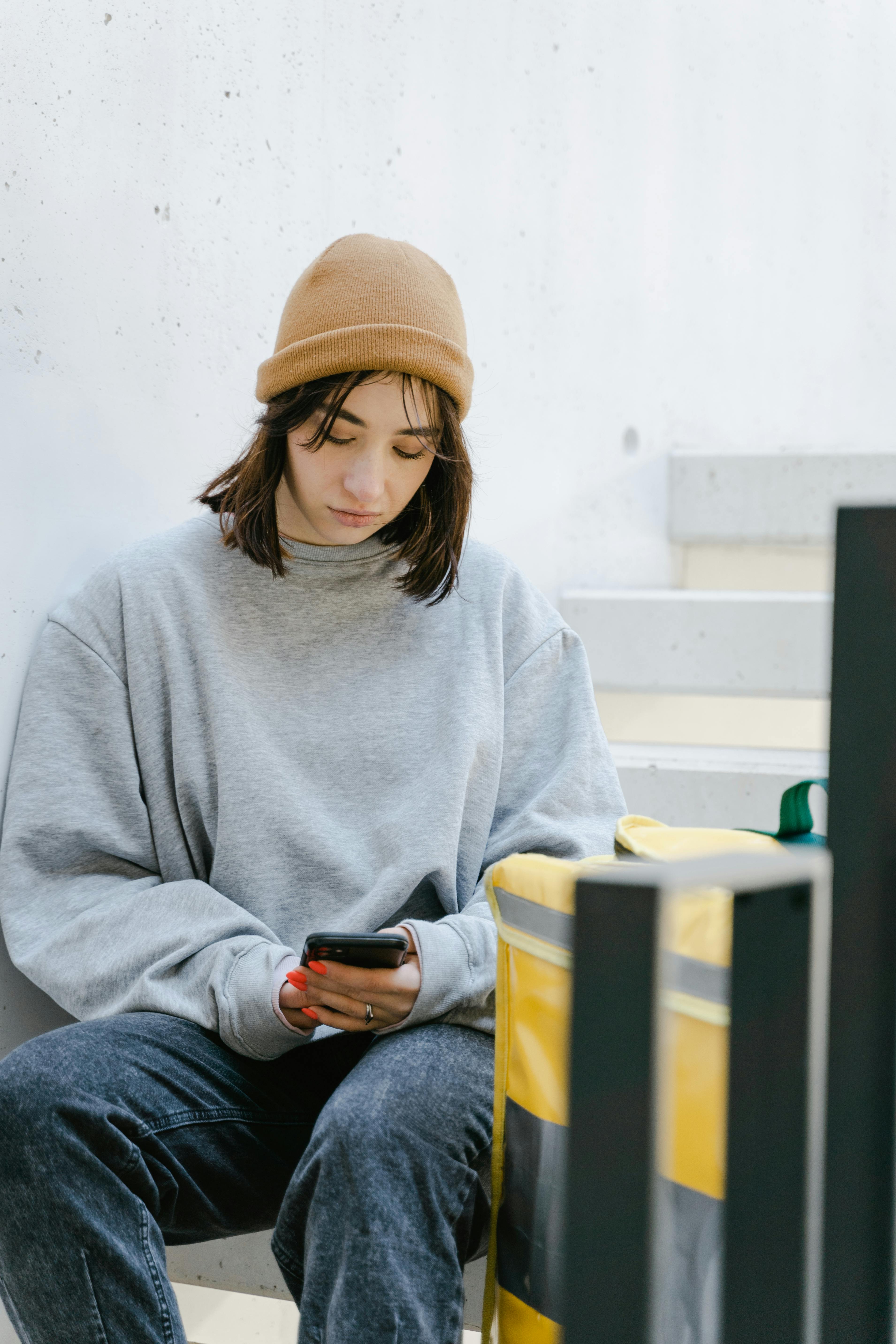 woman in gray sweater and a beanie sitting on the staircase