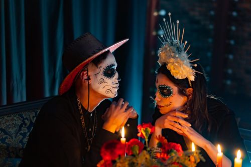 Free A couple in elaborate Día de los Muertos makeup sitting romantically by candlelight. Stock Photo