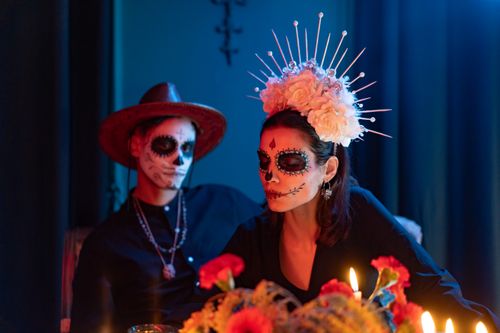 Free Colorful Day of the Dead celebration with face paint and floral headpiece indoors. Stock Photo