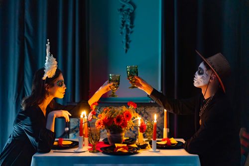 Free A masquerade-themed dinner with candles, flowers, and participants in elaborate makeup, toasting with wineglasses. Stock Photo