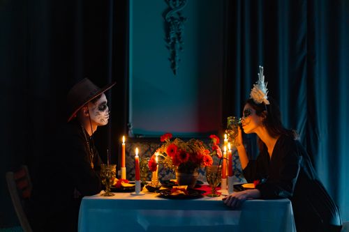 Free A couple with sugar skull makeup enjoys a candlelit dinner with a Day of the Dead theme. Stock Photo