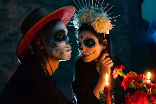 Free A festive scene depicting two adults with Day of the Dead makeup and costumes by candlelight. Stock Photo