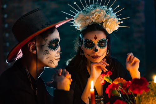 Free Close-up portrait of a couple in Dia de los Muertos costume and makeup, surrounded by candles. Stock Photo
