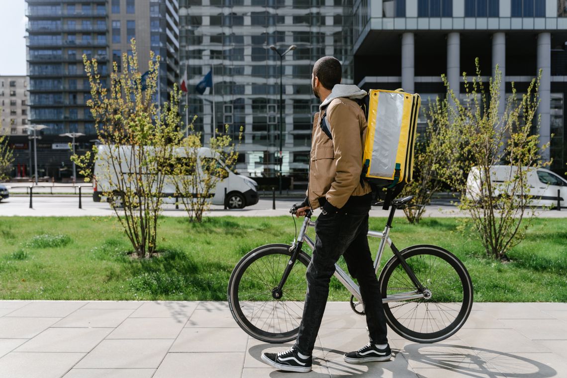 Cyclist walking beside a bicycle in a modern downtown business district
