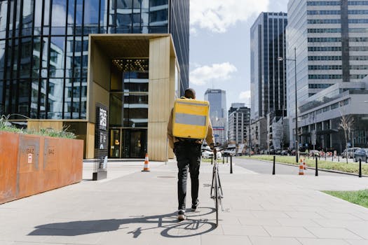 Bicycle courier with a thermal bag delivering food in a modern urban environment.