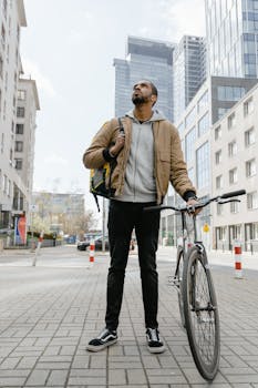 Man with bicycle standing in the city, representing urban transportation and modern delivery services.
