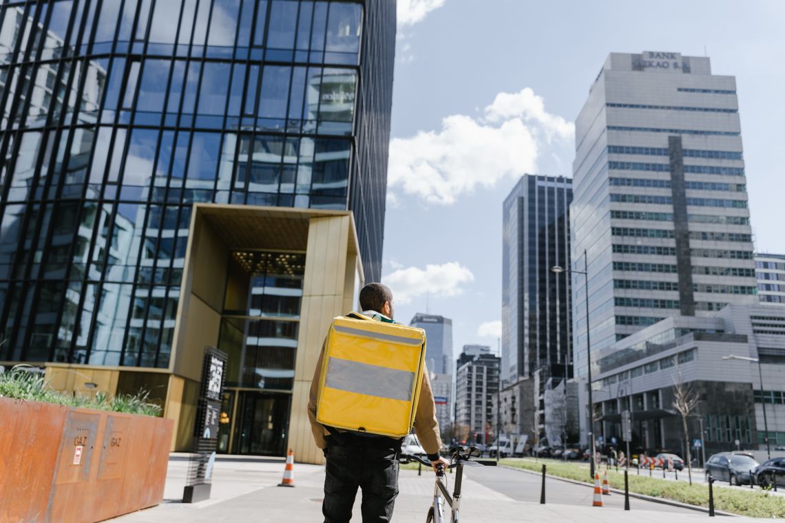 Bicycle courier with a delivery backpack in a modern city business district
