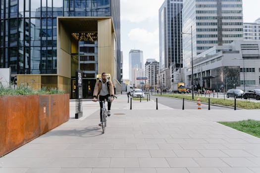 Cyclist delivering food through a modern cityscape in Warsaw, showcasing urban logistics.