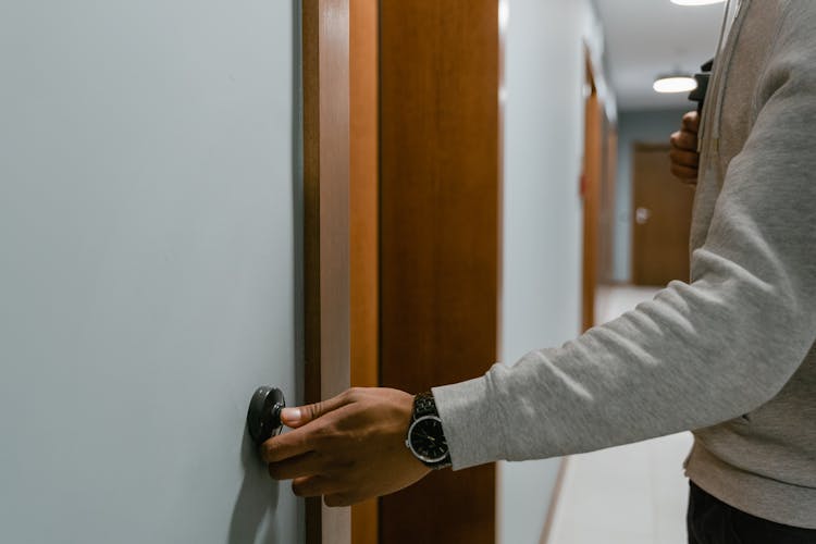 Person In Gray Long Sleeve Shirt Ringing The Doorbell