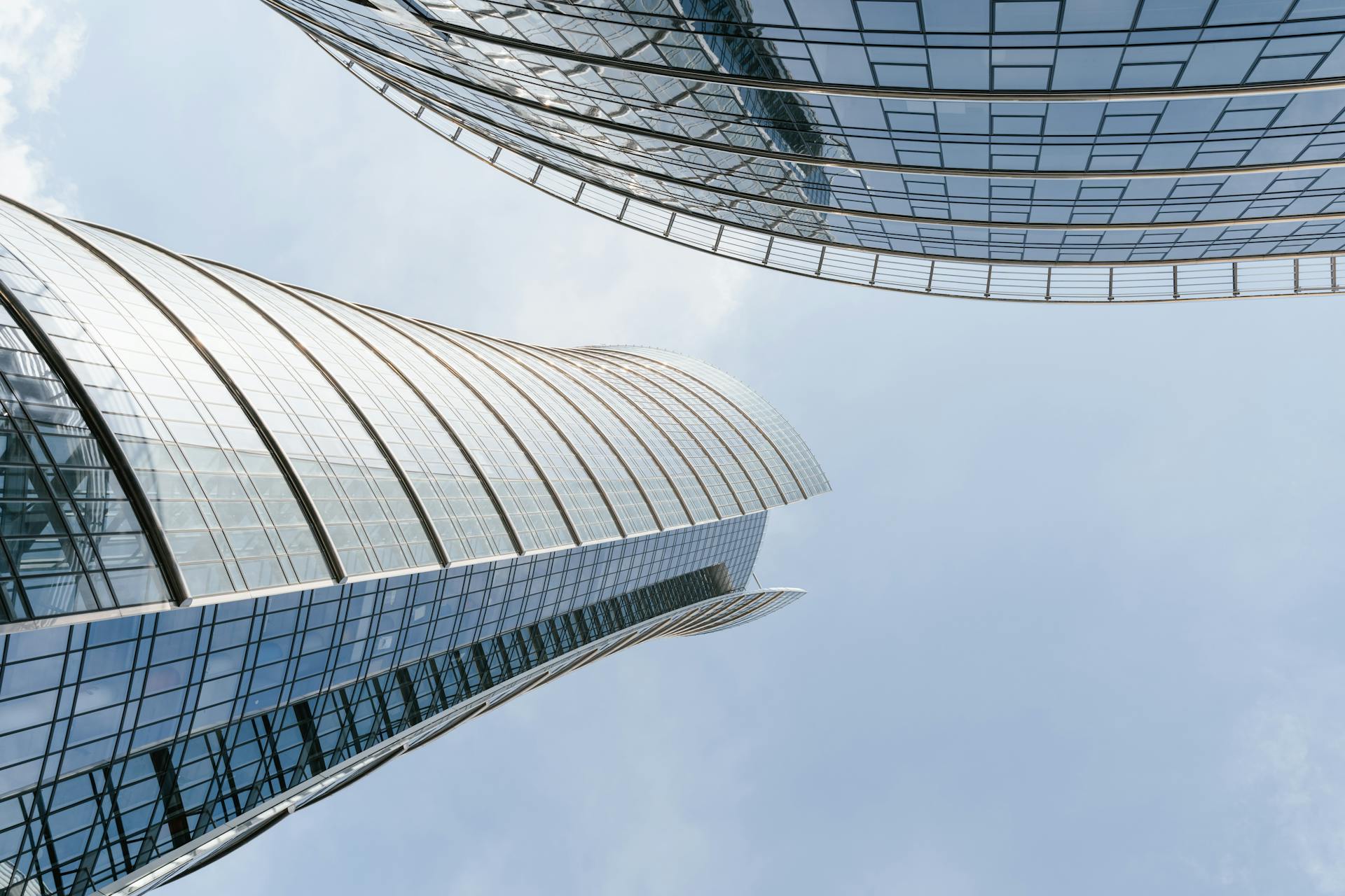 An upward view of sleek, curved skyscrapers against a clear sky.