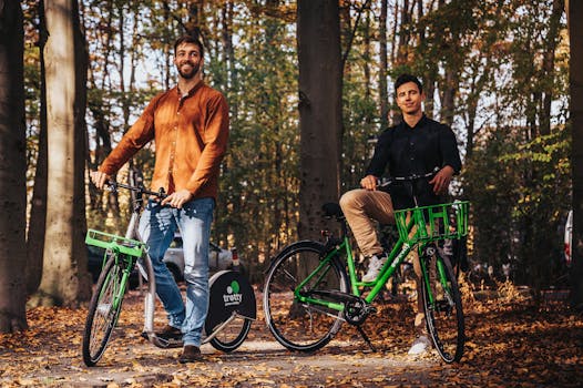 Two men enjoying a bicycle ride in an autumn forest setting, showcasing green rental bikes.