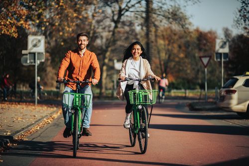 Free Man and woman riding bicycles on a sunny autumn street in a park. Stock Photo