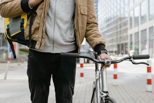 Bicycle courier standing with a bike in an urban setting, ready for delivery.