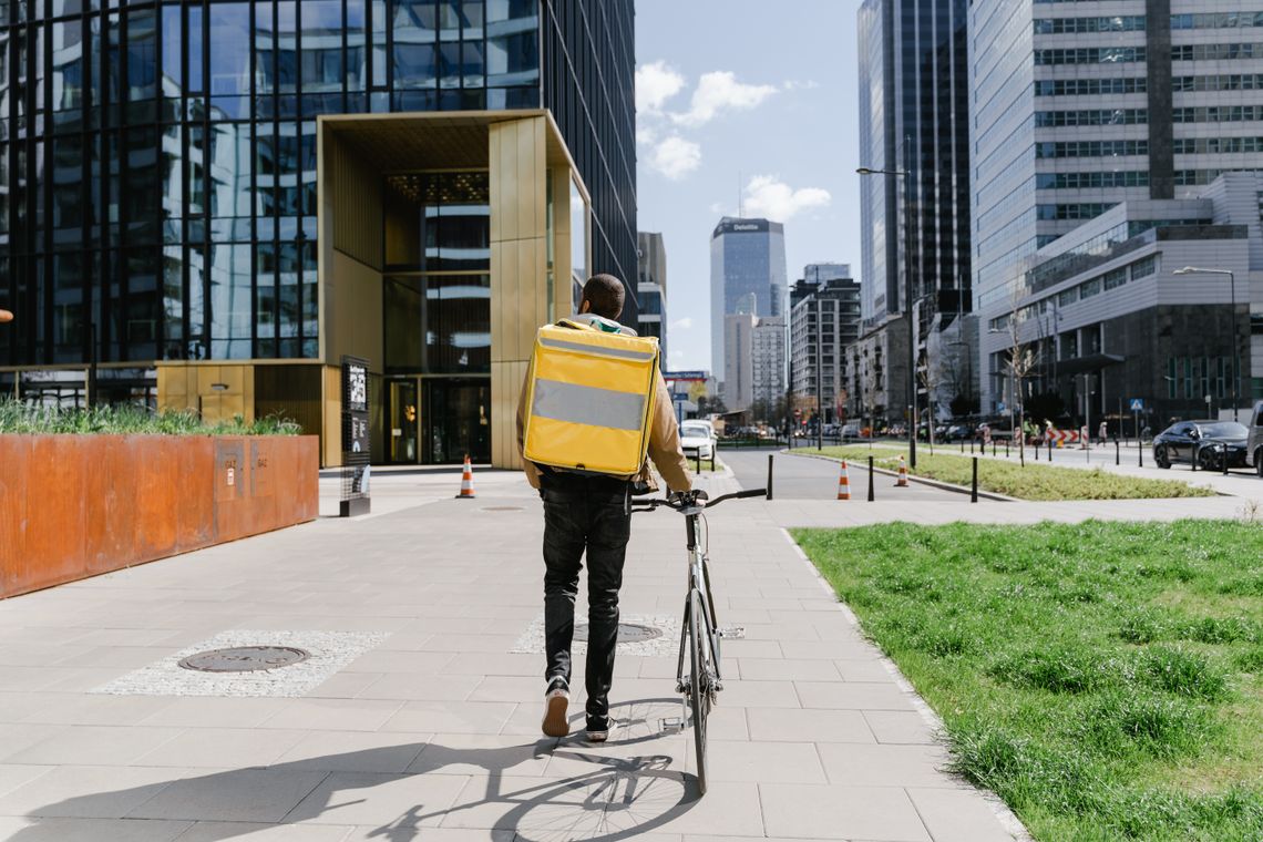 Urban cyclist walking beside a bicycle with a practical carrying bag