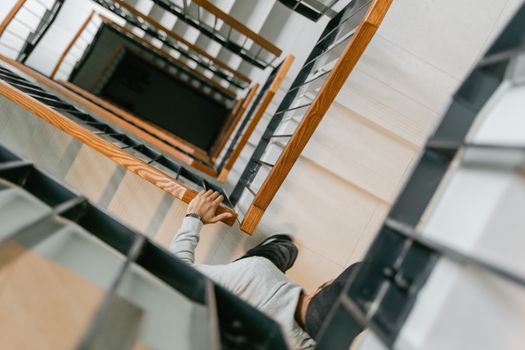 Person descending staircase, captured from above, highlighting geometric lines.