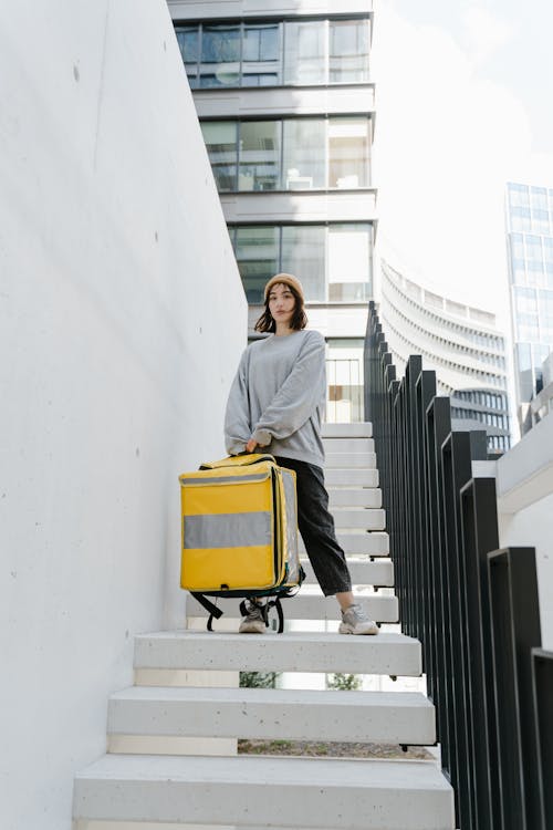 Woman in Gray Sweater Holding a Delivery Bag