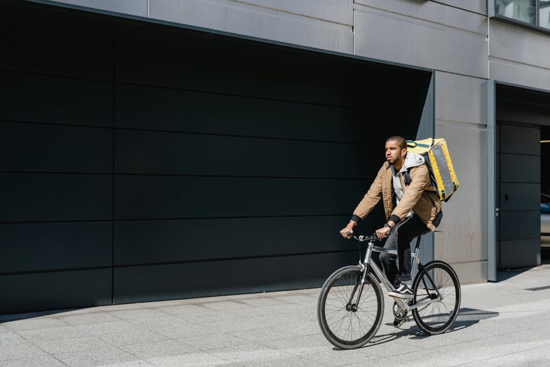 Man in Brown Jacket Riding a Bicycle