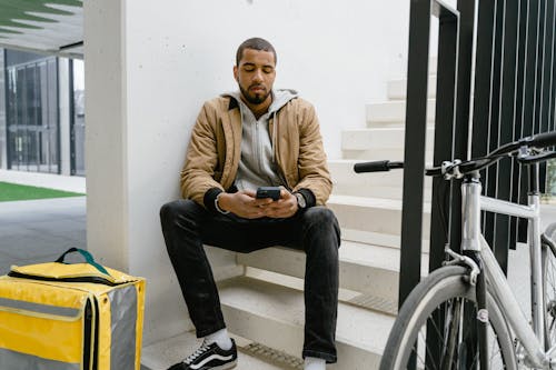 Man in Brown Zip Up Jacket and Black Pants Sitting 