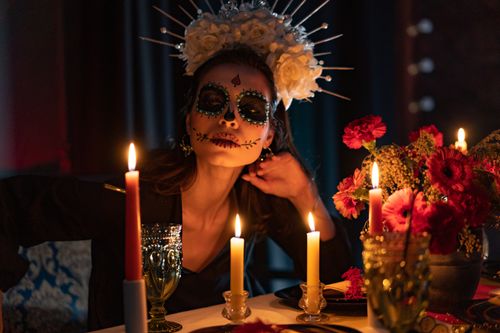 Free A beautifully decorated woman celebrating Día de los Muertos with candles and flowers. Stock Photo