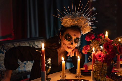 Free Elegant Dia de los Muertos celebration with candlelit ambiance and traditional face paint. Stock Photo