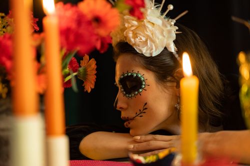 Free A woman with Day of the Dead makeup and floral headpiece in candlelit ambiance. Stock Photo
