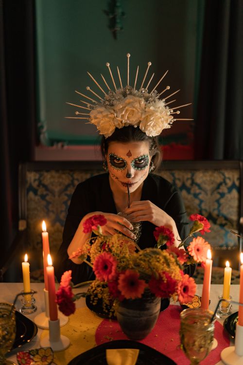 Free A woman with face paint and floral headpiece at a candlelit Day of the Dead altar. Stock Photo